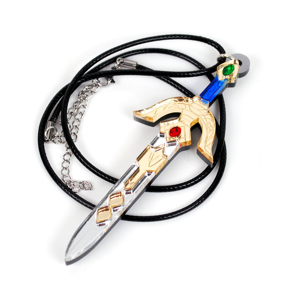 A fantasy sword pendant necklace on a black cord, featuring a gold-colored hilt with red and green gemstone accents, a clear blade, and a silver chain extender, shown on a white background.