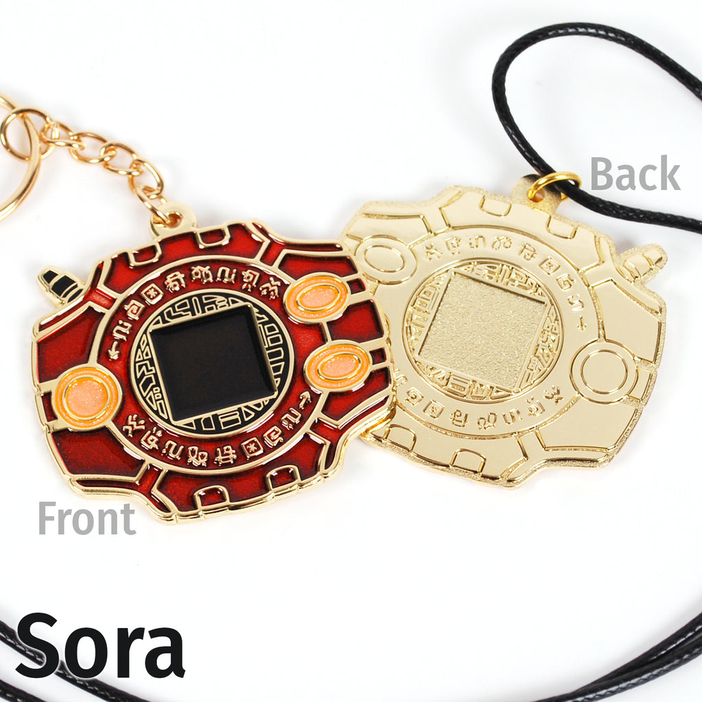 Front and back of Sora digivice, showing red and light orange colors on gold metal with a keychain or necklace attachment.